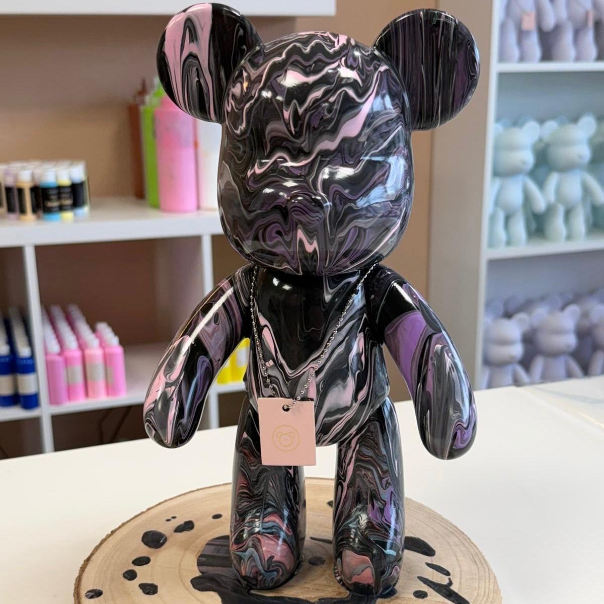  Schwarz lila marmoriert glänzende Soulbear Figur steht auf einer Holzscheibe im Studio